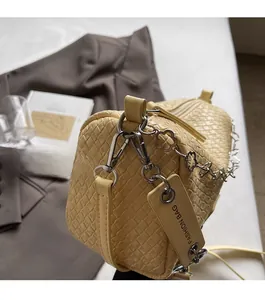 Detail view of yellow woven texture shoulder bag with silver hardware and flower chain