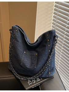 Deep blue denim tote bag with metal rivets and chain strap on a vintage lifestyle background