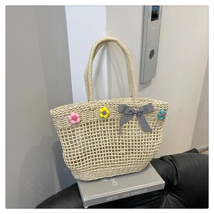 Detail of woven straw tote bag with colorful knitted flowers and a gingham bow
