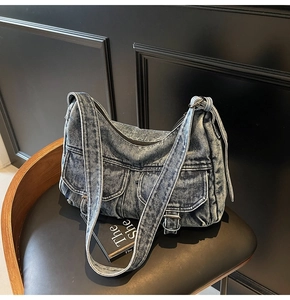 Close-up of vintage washed denim hobo bag featuring dual buckle pockets and texture