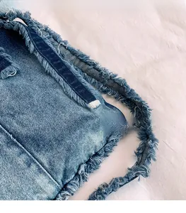 Gros plan sur le tissu denim délavé bleu montrant les détails effilochés de la bandoulière