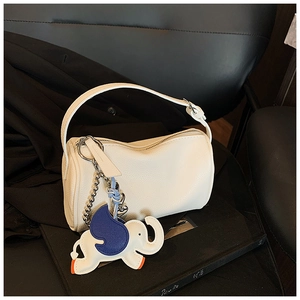 Detail of white lychee grain leather cylinder bag featuring a blue elephant charm