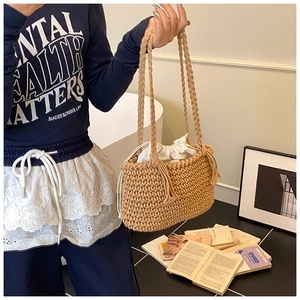 Detailed view of hand-woven bucket bag with beige drawstring pouch and sturdy braided handles