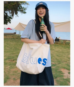 Détail de l'inscription 'blues' bleue sur un grand sac cabas en toile blanche tendance