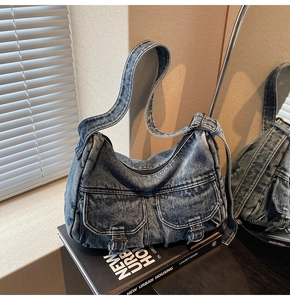 Detail of vintage washed blue denim hobo bag with front buckle pockets on books