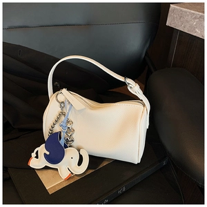 Detail of white lychee grain handbag featuring a cute colorful elephant leather charm