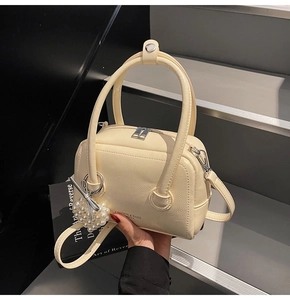 Detailed close-up of beige pillow bag featuring lychee grain texture and pearl heart charm