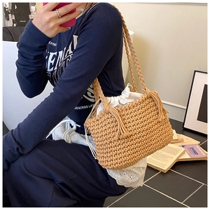 Detail of hand-woven straw bucket bag with drawstring liner and elegant side tassels