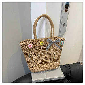 Detailed close-up of handmade straw tote bag with woven flowers and plaid bow detail