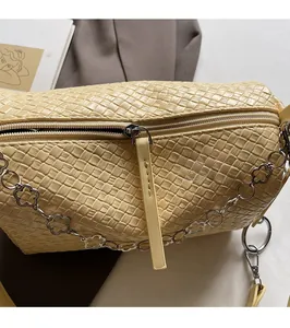 Detail of yellow woven shoulder bag featuring smooth metal zipper and floral chain charm