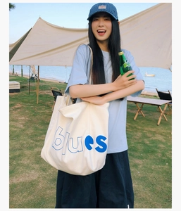 Grand sac cabas en toile blanche avec lettrage bleu dans une scène de camping d'été