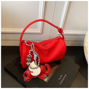 Detail of red litchi leather bag with decorative elephant charm on professional props