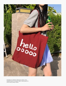 Detail van rode canvas draagtas met witte hello tekst op straatstijl achtergrond