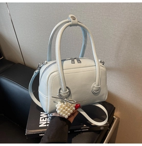 Close-up of light blue leather boston bag with silver heart pearl charm and bow detail