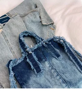 Détail d'un sac cabas en denim patchwork bleu avec bords effilochés et poignées solides