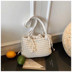 Detail of hand-woven cream cotton bucket bag with stylish side tassels and drawstring liner