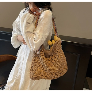Detailed close-up of handmade straw shoulder bag with colorful ethnic pattern strap