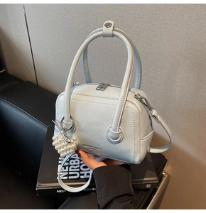Detail of light blue faux leather bag with pearl heart charm and metal ring strap