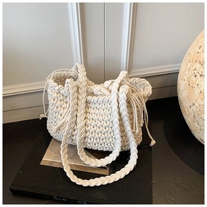 Detail of woven texture on white bucket bag with drawstring inner pouch and strap