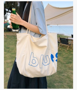 Détail d'un grand sac cabas en toile crème avec lettrage bleu 'blues' en décor extérieur