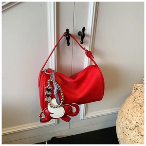 Detail of red pebbled leather pillow bag with elephant charm and silver heart pendant