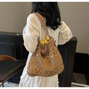 Detail of hand-woven straw tote bag with colorful ethnic embroidered wide strap