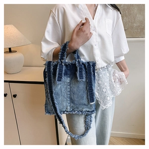 Détails de la texture denim vieilli et des bords effilochés du sac cabas en jean bleu