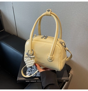 Detailed macro of cream yellow Boston bag with lychee texture and heart pearl charm