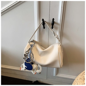 White lychee grain bag detail featuring a cute elephant charm on minimalist leather handle