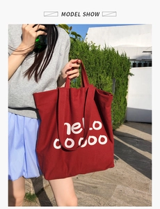 Buitenopname van een rode canvas shopper met witte letters en stevige dubbele hengsels