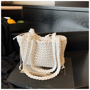 Detailed view of white woven bucket bag with diamond texture and thick braided handle