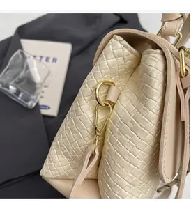 Nahaufnahme der beigen Handtasche mit Webstruktur und hochwertigen goldenen Metallteilen