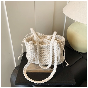 Detail of hand-woven cream bucket bag with intricate texture and drawstring inner pouch