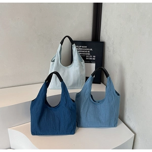 Tre borse tote in denim in varie sfumature di blu con manici in pelle nera resistente