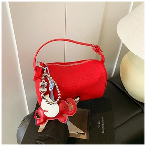 Detail of red pebbled leather cylinder bag with elephant charm and silver bead chain