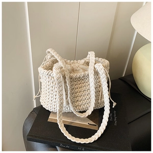 Macro detail of creamy white woven bucket bag showing honeycomb knit texture and drawstring