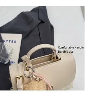 Detailansicht der cremefarbenen Kunstledertasche mit festem Griff und goldener Schließe