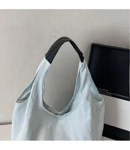 Dettaglio della borsa tote in denim blu con manici neri ergonomici e chiusura magnetica