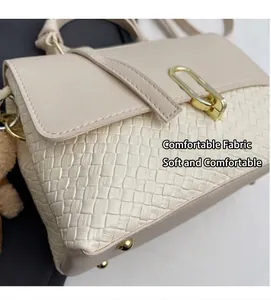 Detail einer beige gewebten PU-Leder Handtasche mit goldener Schnalle und Bärenanhänger