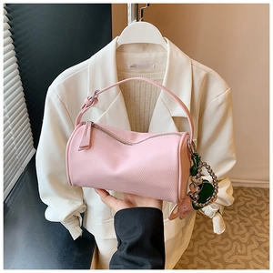 Close-up of pink pebbled leather Boston bag with green heart charm and metal zipper