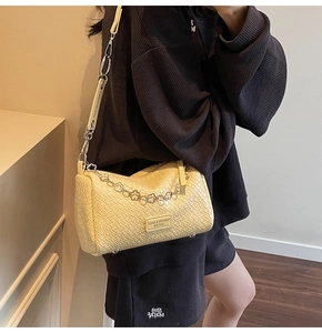 Close-up of beige woven leather cylinder bag with stylish chain and adjustable strap