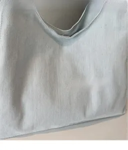 Primo piano della texture in denim azzurro e della chiusura con bottone magnetico in metallo
