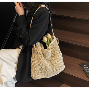 Detail of handmade straw shoulder bag with colorful ethnic embroidered strap on model