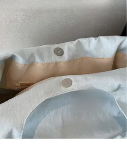 Dettaglio ravvicinato di una borsa tote in denim blu con chiusura magnetica argento
