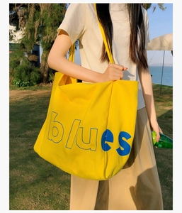 Gros plan d'un grand sac cabas en toile jaune avec motif artistique lettré bleu