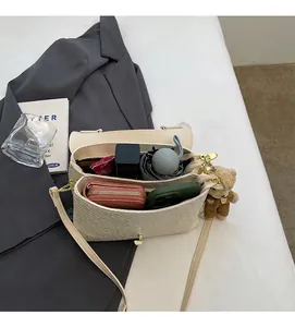 Detailansicht der beige gewebten Handtasche mit großem Innenraum und Bärenanhänger