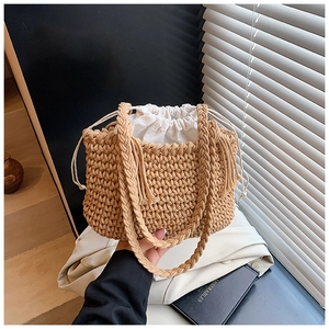 Detail of hand-woven straw bucket bag with white canvas drawstring liner and dual handles
