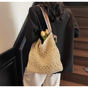 Detail of woven straw tote bag with ethnic style shoulder strap and crochet hollow design