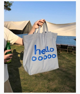 Detail van canvas draagtas met hello ooooo print en dubbele handvatten in de buitenlucht