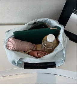 Dettaglio della grande borsa tote in denim con tablet, ombrello e bottiglia all'interno